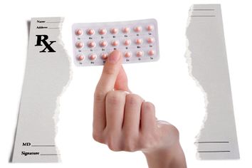The pill - hand holding contraceptives against a white backgroun