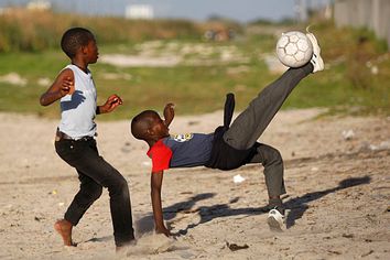 Members of the Stars of Tomorrow soccer team play on a narrow strip of open ground between a busy highway and Khayelitsha township