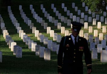 An honor guard taking part in a wreath laying ceremony  walks past the gravestones at Arlington National Cemetery outside Washington