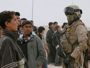 Residents look at a U.S. marine providing security to international election observers in Sinjar