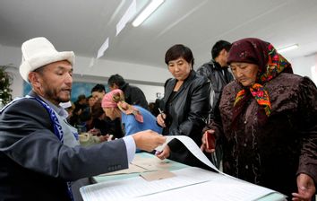A woman receives ballot papers at a polling station during parliamentary elections in the village of Koy-Tash