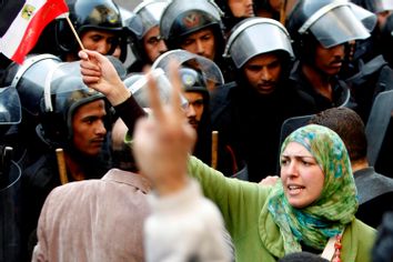 A woman holds an Egyptian flag in front of riot police during a protest in Cairo