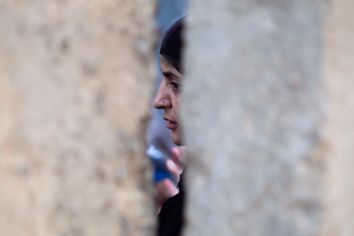 A Palestinian woman waits behind a wall after she was refused entry to cross into Jerusalem from Israel's Qalandiya checkpoint outside Ramallah