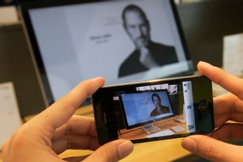A man uses his iPhone to photograph image of Steve Jobs