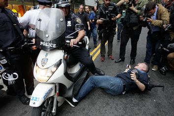 A New York City police officer runs over a National Lawyers Guild observer as Occupy Wall Street demonstrators march through the streets near Wall Street, Friday, Oct. 14, 2011, in New York.