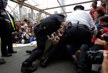 Police officers reach into a crowd of protesters to make an arrest on the Brooklyn Bridge during an Occupy Wall Street march in New York