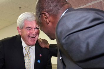 Newt Gingrich (L), former speaker of the U.S. House of Representatives, laughs with Herman Cain