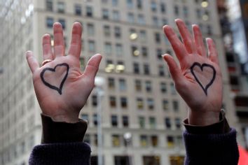 An Occupy Wall Street demonstrator raises her hands painted with hearts