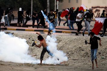 An anti-government protester throws a tear gas canister back to riot-police during clashes in the village of Aali, south of Manama November 26, 2011.