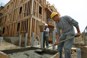 A worker shovels wet concrete at a residential site in Los Angeles, California