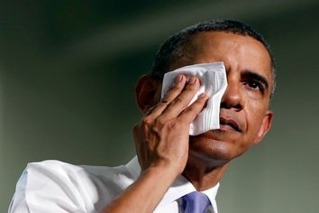 U.S. President Barack Obama wipes his face in the heat at a campaign event at Oyster River High School in Durham