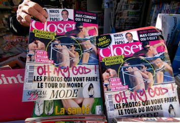 A man holds a copy of the French magazine Closer showing pictures of Catherine, Duchess of Cambridge, and Britain's Prince William are displayed in a newspaper kiosk in Nice