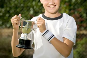 Young boy holding a trophy on a tennis court