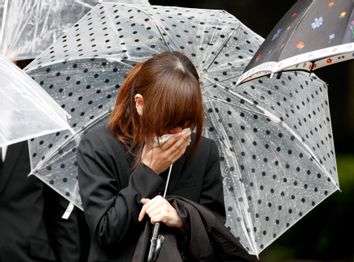 Mourner cries after sending off hearse carrying coffin of twenty-one-year-old Mai Muto in Tokyo