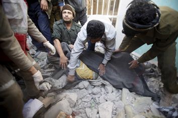 Policemen and medics cover the body of a dead man, that they recover from the site of a Saudi-led air strike on the police headquarters in Yemen's capital Sanaa