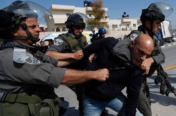 Israeli border policemen detain a Palestinian protester during a protest against what Palestinians say is land confiscation by Israel for Jewish settlements, near the West Bank town of Abu Dis