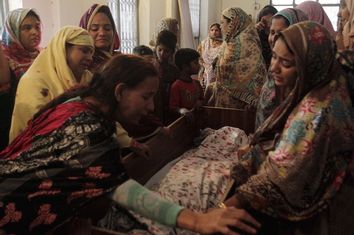 Family members mourn the death of a relative, who was killed in a blast that happened outside a public park on Sunday, in Lahore