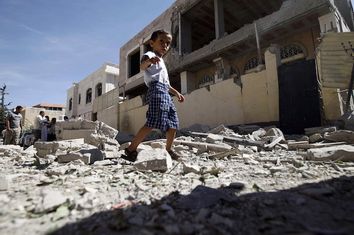 Boy walks past a house damaged by a Saudi-led air strike in Yemen's capital Sanaa