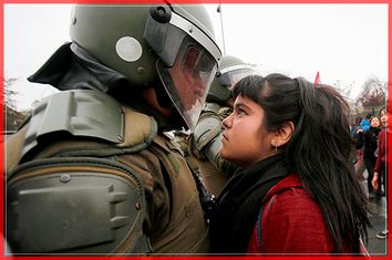 A demonstrator looks at a riot policeman during a protest marking the country's 1973 military coup in Santiago, Chile