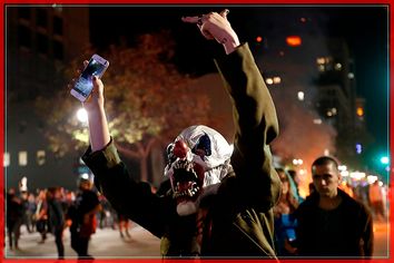 A masked demonstrator gestures toward a police line during a demonstration in Oakland, California, U.S. following the election of Donald Trump as President of the United States