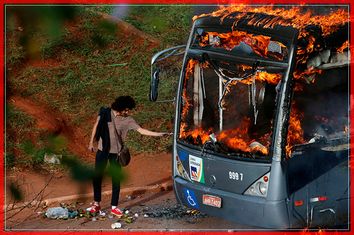 A man lights up his cigarette with the flames of a bus burned by anti-government demonstrators during a protest against the constitutional amendment PEC 55, which limits public spending, in front of Brazil's National Congress in Brasilia