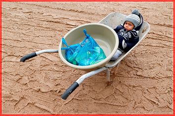 A young displaced Iraqi boy who fled the Islamic State stronghold of Mosul sits in a wheelbarrow at Khazer camp Iraq