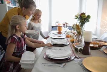 Grandmother and granddaughters setting the table for Thanksgiving dinner