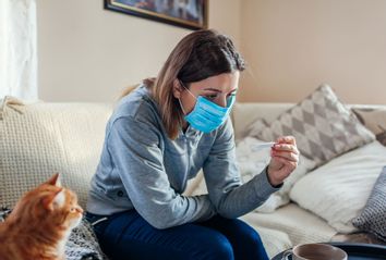 Ill woman checking thermometer having fever