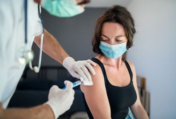 Woman with face mask getting vaccinated