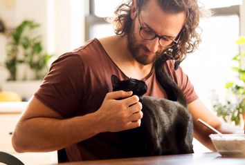Young man stroking his black cat