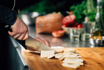 Chef Cutting Tofu On A Wooden Cutting Board