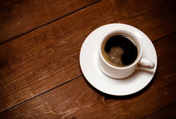 White cup of coffee on old wooden table