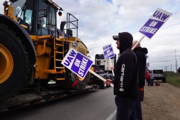 A truck hauls a piece of Deere equipment from the factory past workers picketing outside of the John Deere Davenport Works facility on October 15, 2021 in Davenport, Iowa.