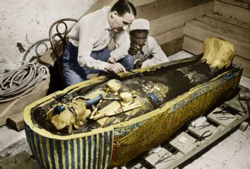 English Egyptologist ﻿Howard Carter near golden sarcophagus of Tutankhamen mummy in Egypt