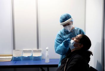 A health worker takes a swab sample from a woman at a COVID-19 testing center