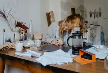 Emotionally stressed businesswoman with coffee cup at table in living room