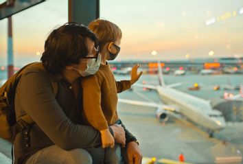 Family in protective face masks in airport during COVID-19 pandemic