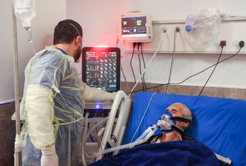 A medical worker monitors the vitals of an intubated patient at the COVID-19 coronavirus ward