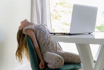 Yong girl leaning back, distracted during at-home learning on computer