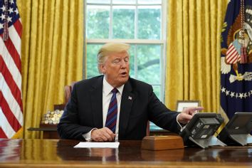 Donald Trump looks at his telephone from the Oval Office