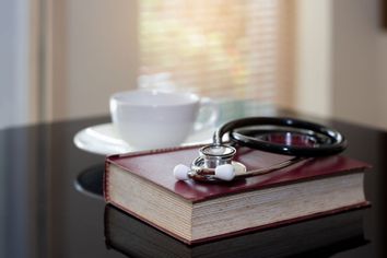 Desk with a medical stethoscope, a book and a cup of coffee