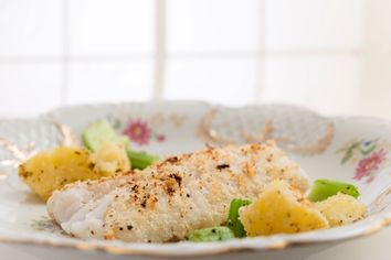 Decorative plate with fried breaded fish, sautéed chopped celery and cooked and fried potatoes