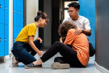 Two students comfort a classmate in the corridor