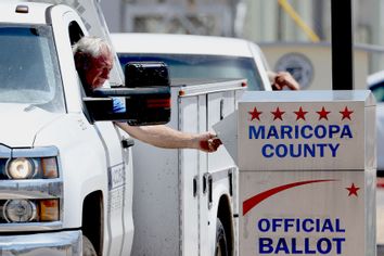 A voter places a ballot in a drop box outside of the Maricopa County Elections Depart