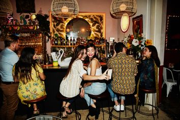 Female friends taking selfie with smart phone while sitting at bar