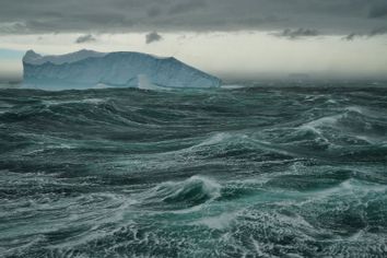 Tabular iceberg floats in a stormy green sea, Southern Ocean, Antarctica