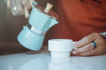 Man pouring coffee from a moka pot into a cup