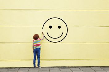 Girl drawing smiley face on to a wall