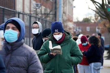 A man reads a book while waiting on line at a mobile Covid-19 test site.