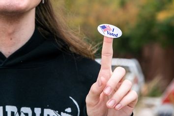 A young man who just voted shows his voting sticker